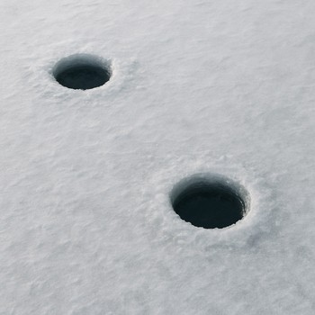 Two ice holes drilled a few meters apart on a wide frozen lake