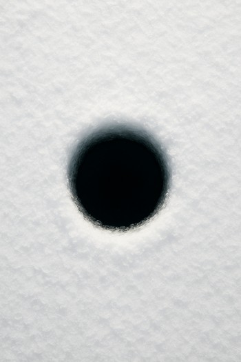 Top view of a single round ice hole with rod across it