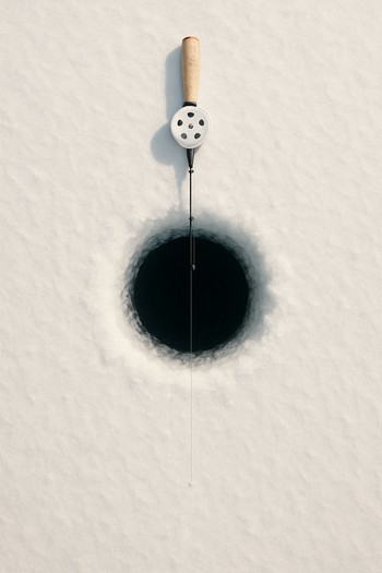 Round ice hole with rod across it seen from above